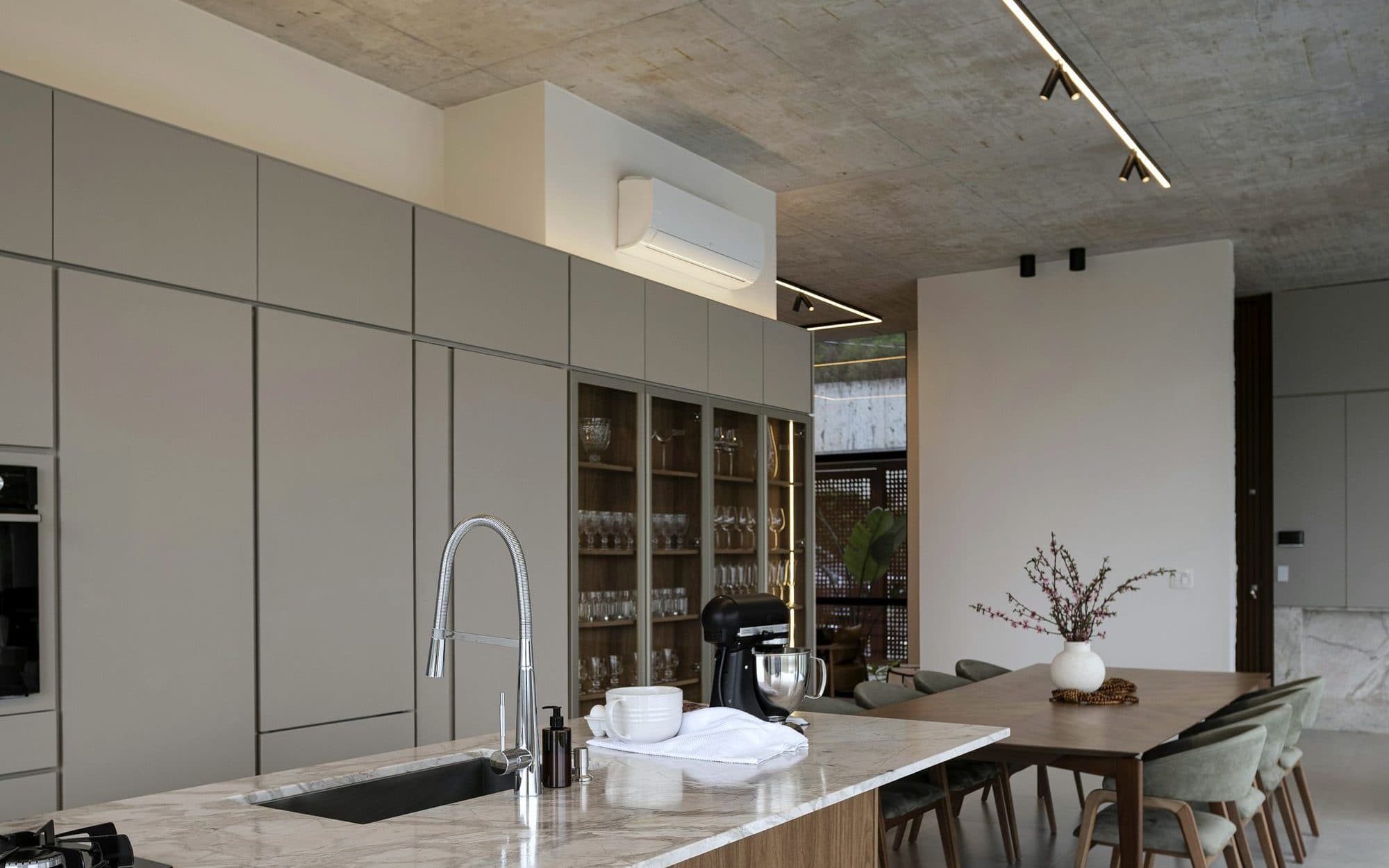 Cuisine ouverte contemporaine, bois et béton, équipée d’une unité de climatisation